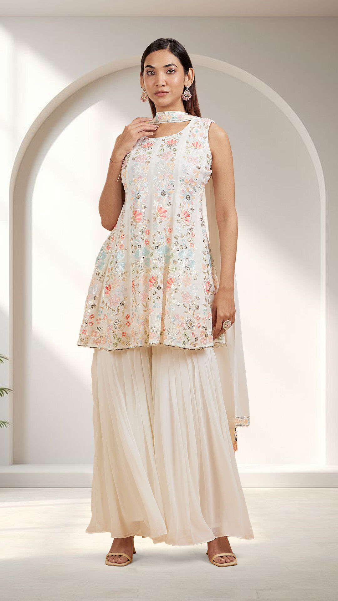 Woman wearing floral embroidered pastel kurti with flared palazzo pants, posing gracefully against an elegant archway backdrop — Onam festive wear for women 2025.